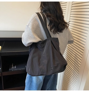 Detail of black tote bag showing smooth nylon texture and white Chuangmei woven label