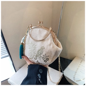 Detailed close-up of vintage shell bag with bird embroidery and cyan blue tassel