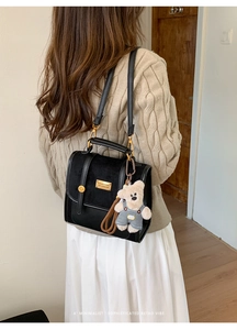Detail of vintage black patchwork backpack with gold hardware and a cute teddy bear charm
