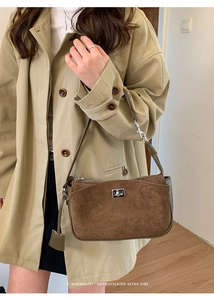 Detail of a brown suede shoulder bag with a silver twist-lock and minimalist retro design