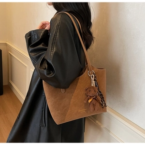 Gros plan sur un sac cabas marron en daim avec breloque d'ours et détails de glands