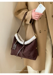 Detail of dark brown suede tote bag with white shearling trim on a model shoulder