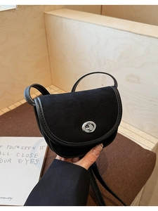 Close-up of black saddle bag with matte suede flap and silver twist-lock closure detail