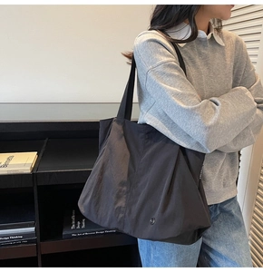Large black nylon tote bag for women shown on shoulder in a modern setting