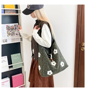 Detail of dark green knit tote bag featuring white floral embroidery and drawstring closure