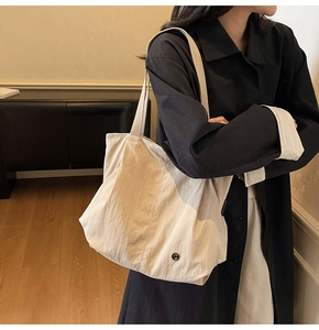 Detailed close-up of beige tote bag fabric and woven side label on a shoulder bag