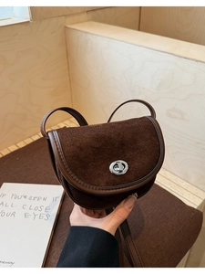 Detail of vintage suede saddle bag in dark brown with a silver metal twist lock
