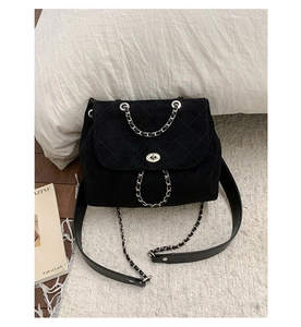 Detail of black quilted velvet backpack with silver twist lock and chain strap