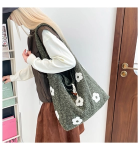 Close-up of forest green plush tote bag featuring 3D white floral embroidery details