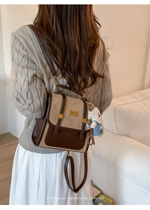 Detail of retro brown and beige backpack with teddy bear pendant on a model