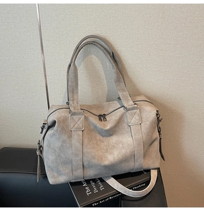 Detailed close-up of handle stitching and suede texture on a taupe tote bag