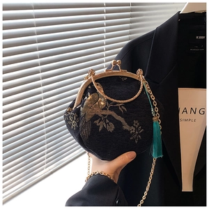 Detail of vintage black shell bag featuring golden bird embroidery and blue silk tassel