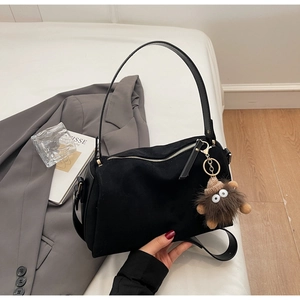 Detail of black matte suede pillow bag with golden zipper and plush monster charm