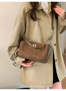 Detail of a brown suede shoulder bag with silver clasp and leather trim on a model