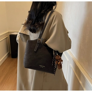 Détail d'un grand sac cabas vintage avec charm ours et texte de marque gravé