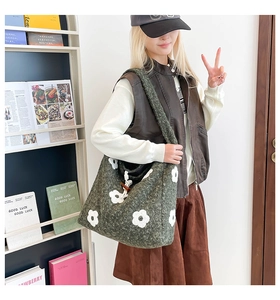 Detail of green plush tote bag with white flower embroidery and wooden toggle closure