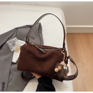 Brown suede pillow bag featuring a wide shoulder strap and a cute monster plush charm