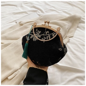 Close-up of black floral jacquard bag with gold metal clasp and green tassel charm