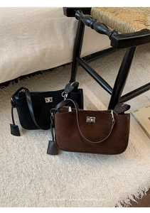 Detail view of vintage suede shoulder bag with metal twist lock on a plush rug