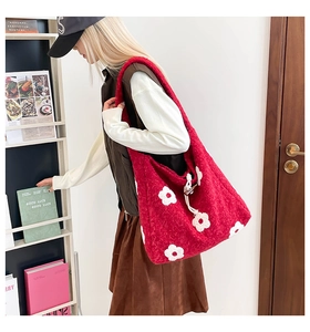Detail of red plush tote bag with white flower embroidery and wooden toggle closure