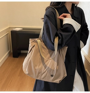 Detail of khaki tote bag with textured nylon fabric and premium round metal logo