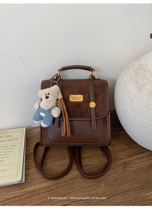 Detailed shot of retro brown leather backpack with gold buckle and teddy bear charm