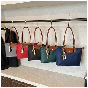 Vue détaillée des sacs fourre-tout en nylon coloré avec poignées en cuir et breloques à glands