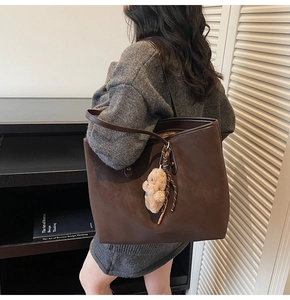 Detail einer dunkelbraunen großen Shopper-Tasche mit süßem Plüschbären und Webband