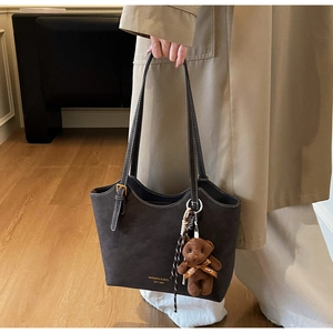 Détail du sac cabas marron foncé en daim avec un pendentif en peluche petit ours