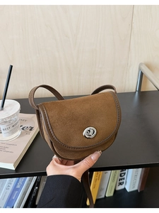 Detail of a brown matte saddle bag featuring a silver twist lock and slim leather strap