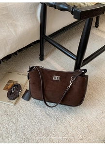 Detail of dark brown suede shoulder bag with silver turn-lock and detachable strap