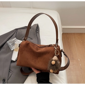 Detailed view of brown matte suede pillow bag with plush charm and wide leather handle