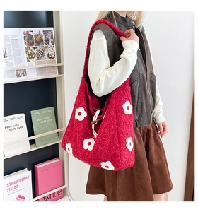 Detail view of red plush tote bag with white floral embroidery and toggle closure