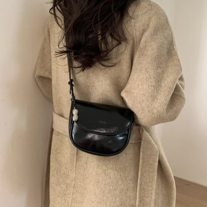 Detail of black semi-circular saddle bag with L.M.L. embossing and silver peanut charm