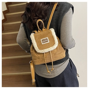 Detail of a brown suede mini backpack with plush fleece trim and a cute bear patch