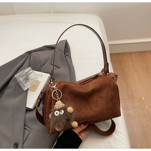 Detailed shot of brown suede crossbody bag featuring a cute furry monster bag charm