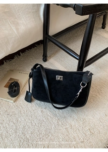 Retro black suede underarm bag with silver lock and spare strap on white rug