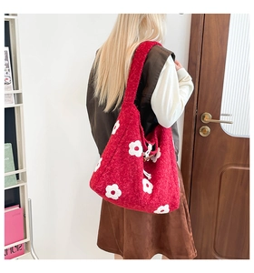 Detail of red plush floral shoulder bag with toggle closure shown on person