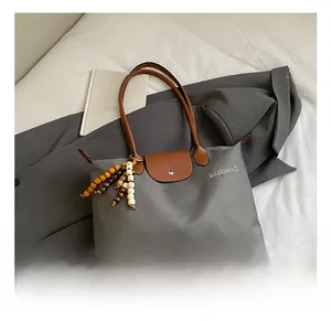 Gros plan du sac à main gris avec poignées en cuir marron et pendentif en perles de bois