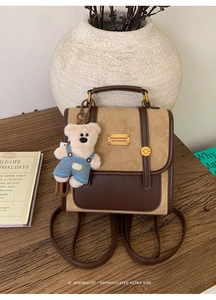 Detail of vintage brown leather backpack with bear pendant and gold buckle on wood surface