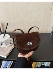 Detail of dark brown saddle bag with matte texture and silver metallic buckle closure