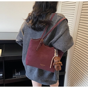 Détail du sac cabas en cuir bordeaux avec lettrage de marque et breloque ours brun