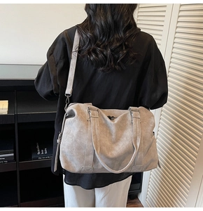 Close-up of grey oversized suede tote bag with fringe tassels and long shoulder strap