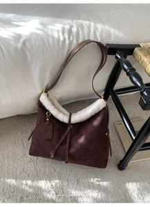 Close-up of vintage brown suede shoulder bag with soft faux shearling trim and tassel detail