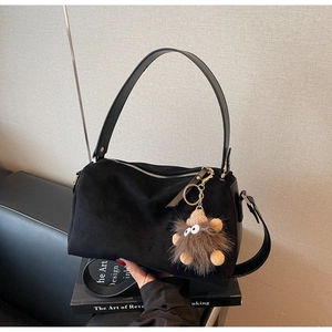 Detail of black suede pillow bag showing matte texture and cute plush monster charm