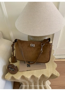 Detailed view of brown suede shoulder bag with silver clasp and retro aesthetic