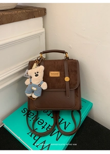 Detail view of vintage dark brown backpack texture with cute plush bear charm accessory