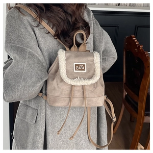 Detail of beige suede mini backpack with plush faux fur trim and bear patch on flap