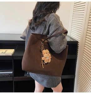 Detailansicht einer großen braunen Wildleder-Tote-Bag mit einem niedlichen Plüschbär-Anhänger