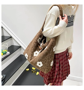 Detailed view of plush brown tote bag featuring white floral embroidery and toggle closure
